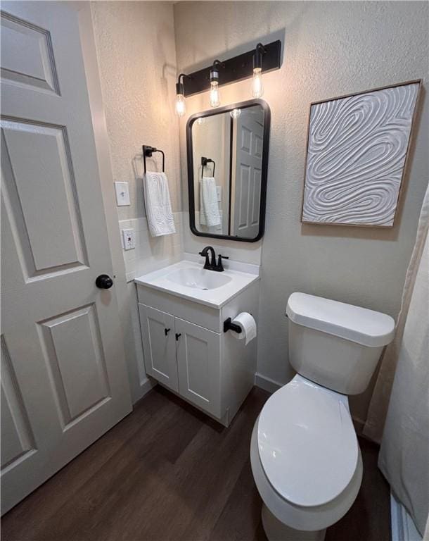 bathroom with hardwood / wood-style flooring, vanity, and toilet