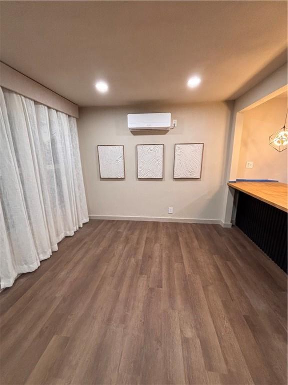 interior space with dark hardwood / wood-style flooring and an AC wall unit