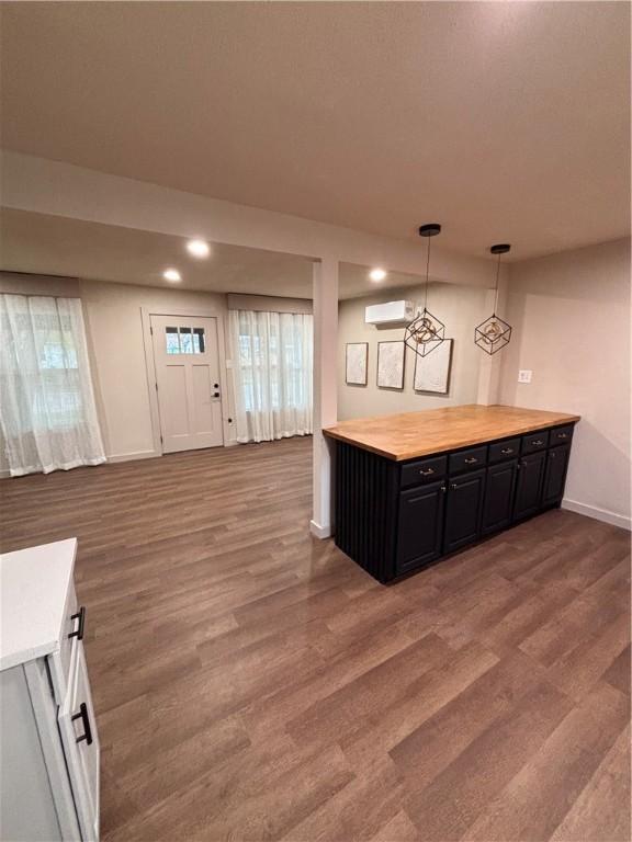 kitchen featuring a wall mounted air conditioner, decorative light fixtures, butcher block counters, and hardwood / wood-style floors