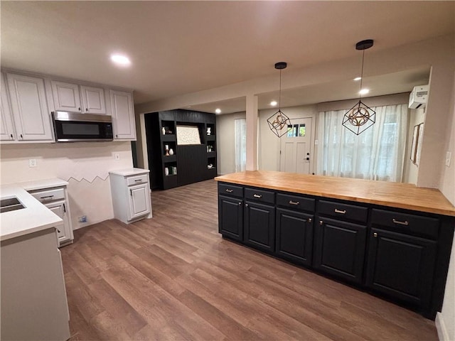 kitchen with white cabinetry, decorative light fixtures, and wooden counters