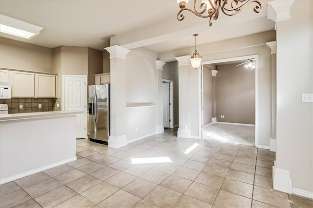 interior space with stainless steel refrigerator with ice dispenser, light countertops, white microwave, a ceiling fan, and ornate columns