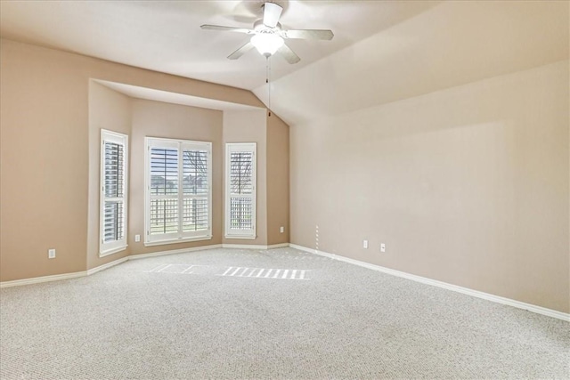 carpeted empty room featuring a ceiling fan, vaulted ceiling, and baseboards