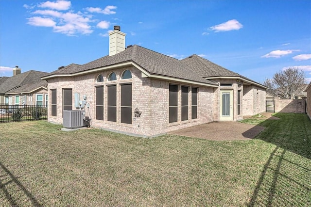 rear view of property featuring brick siding, a chimney, central air condition unit, a lawn, and a fenced backyard