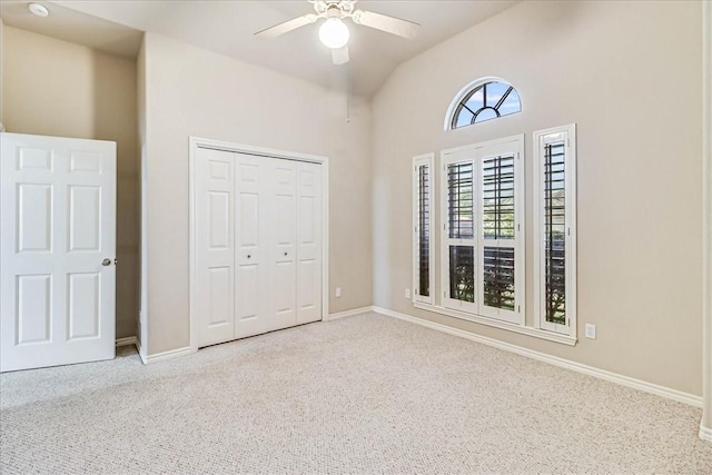 unfurnished bedroom featuring ceiling fan, high vaulted ceiling, carpet floors, baseboards, and a closet