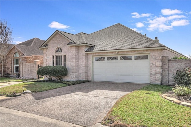 view of front of home with brick siding, a shingled roof, fence, a garage, and driveway