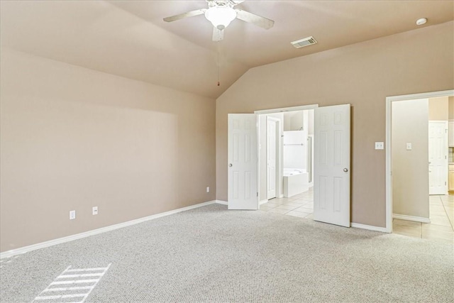 unfurnished bedroom featuring light tile patterned floors, lofted ceiling, ensuite bathroom, light carpet, and visible vents