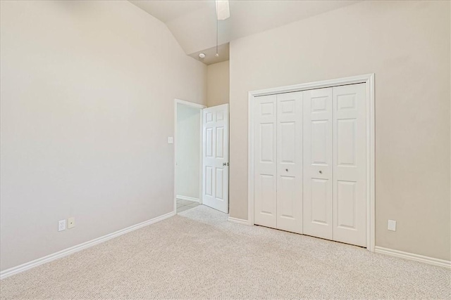 unfurnished bedroom with lofted ceiling, baseboards, a closet, and light colored carpet