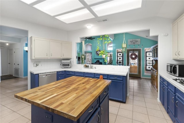 kitchen with blue cabinetry, a center island, kitchen peninsula, white cabinets, and appliances with stainless steel finishes