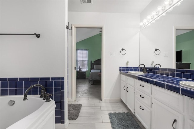 bathroom featuring vanity, a tub, and vaulted ceiling