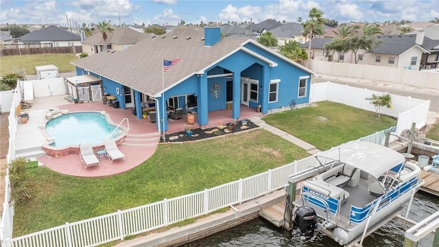 rear view of property with a water view, a fenced in pool, a patio, and a yard