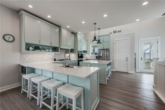 kitchen with stainless steel appliances, kitchen peninsula, backsplash, dark wood-type flooring, and pendant lighting