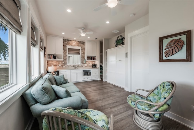 living room featuring dark hardwood / wood-style flooring, ceiling fan, and sink