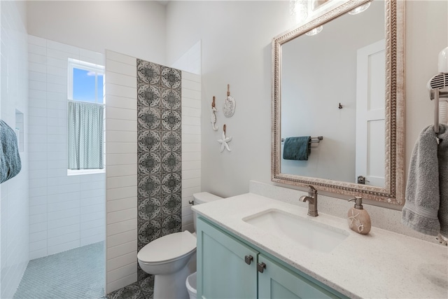 bathroom featuring vanity, toilet, and a tile shower