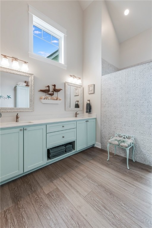 bathroom with high vaulted ceiling, wood-type flooring, and vanity