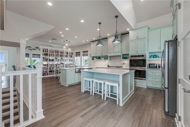 kitchen featuring hanging light fixtures, a healthy amount of sunlight, appliances with stainless steel finishes, and a center island