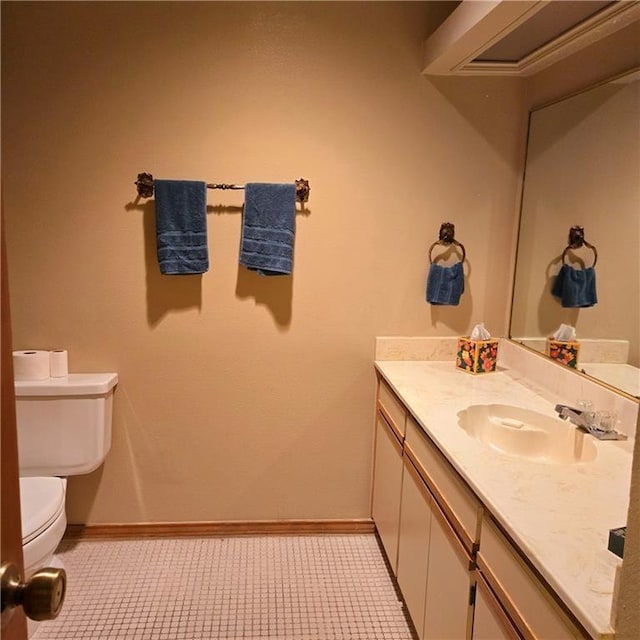 half bath featuring tile patterned flooring, vanity, toilet, and baseboards