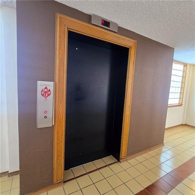 interior space featuring a textured ceiling, baseboards, and elevator