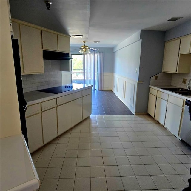 kitchen featuring cream cabinets, light countertops, a sink, and black electric stovetop