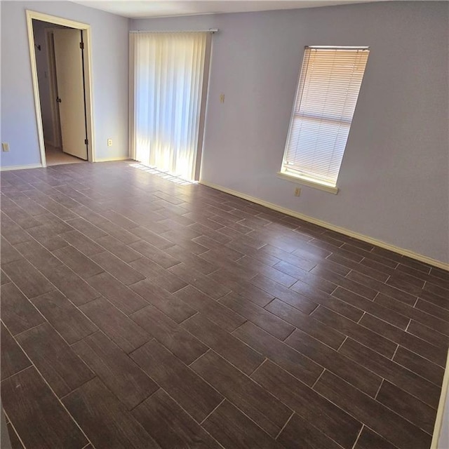 spare room featuring dark wood-style floors and baseboards