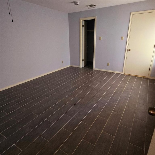 empty room featuring baseboards, visible vents, and wood finish floors