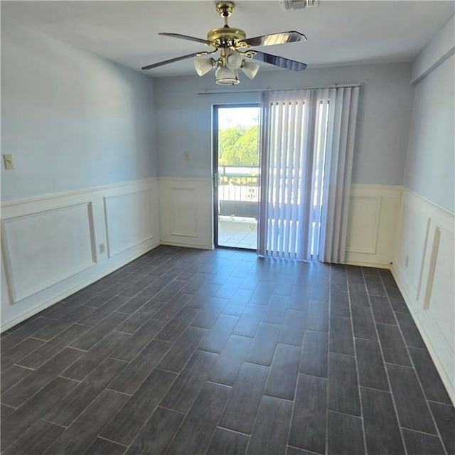 spare room featuring a wainscoted wall, wood finish floors, and a ceiling fan