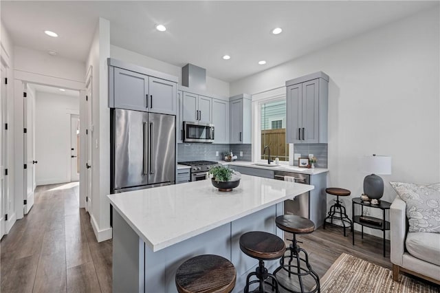 kitchen with a kitchen island, sink, dark hardwood / wood-style flooring, a kitchen breakfast bar, and high end appliances