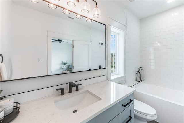 full bathroom featuring vanity, tiled shower / bath combo, and toilet