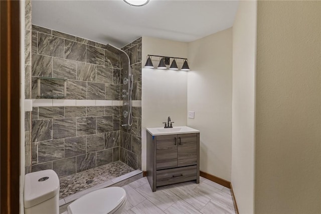 bathroom with a tile shower, vanity, and toilet