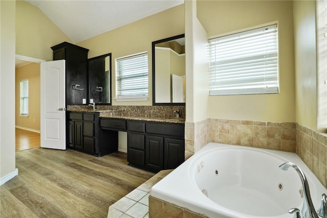 7445 Lake Micala Dr, Corpus Christi, TX 78413 - full bathroom with double vanity, healthy amount of natural light, a jetted tub, lofted ceiling, and wood finished floors
