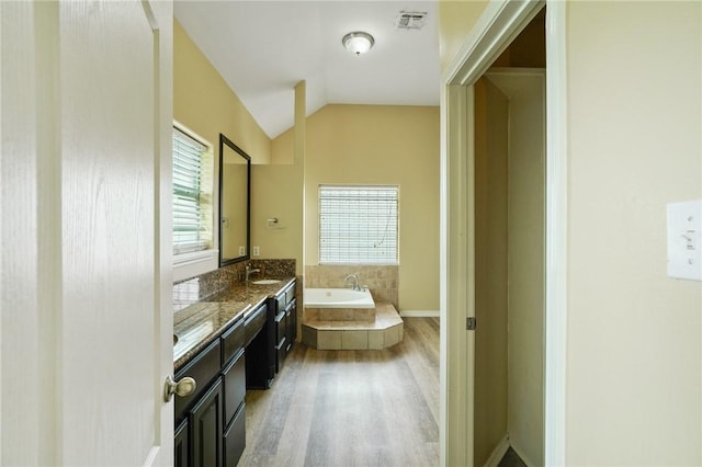 7445 Lake Micala Dr, Corpus Christi, TX 78413 - bathroom with double vanity, wood finished floors, a garden tub, and vaulted ceiling