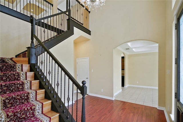 7445 Lake Micala Dr, Corpus Christi, TX 78413 - staircase with arched walkways, wood finished floors, a high ceiling, and a chandelier