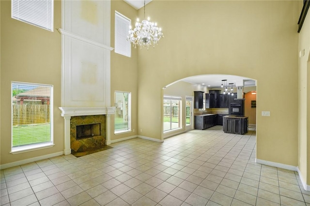 7445 Lake Micala Dr, Corpus Christi, TX 78413 - unfurnished living room featuring a towering ceiling, a chandelier, arched walkways, a premium fireplace, and healthy amount of natural light
