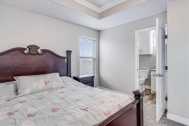 bedroom featuring a tray ceiling, connected bathroom, and baseboards