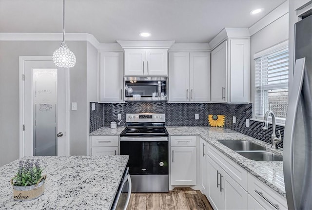 kitchen with tasteful backsplash, white cabinets, light wood-style flooring, stainless steel appliances, and a sink