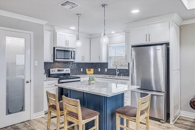 kitchen with a breakfast bar, visible vents, backsplash, appliances with stainless steel finishes, and white cabinets