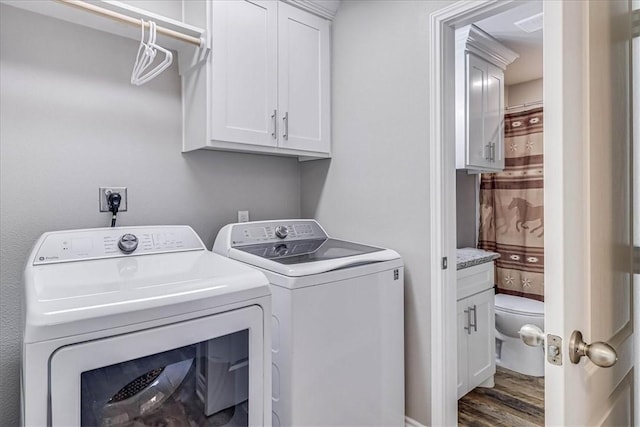 laundry room with dark wood-style floors, washing machine and dryer, and cabinet space