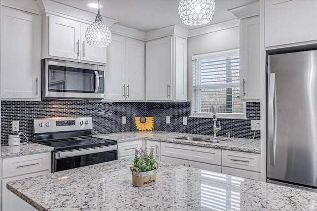 kitchen with stainless steel appliances, a sink, white cabinetry, and decorative backsplash