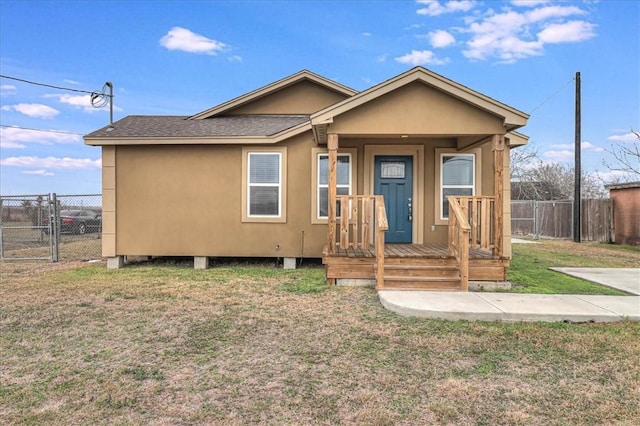 view of front of house featuring a porch, fence, roof with shingles, a gate, and a front lawn