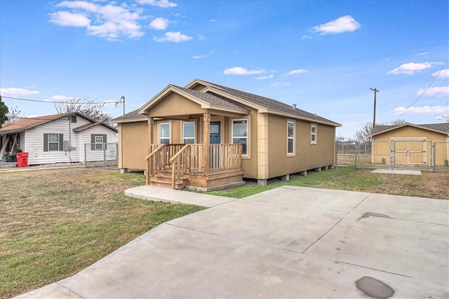 bungalow with an outdoor structure, fence, a front lawn, and roof with shingles