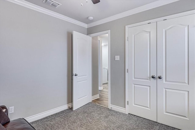 unfurnished bedroom featuring visible vents, baseboards, ornamental molding, carpet, and a closet