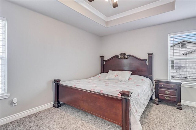 bedroom featuring ceiling fan, a tray ceiling, light colored carpet, and baseboards