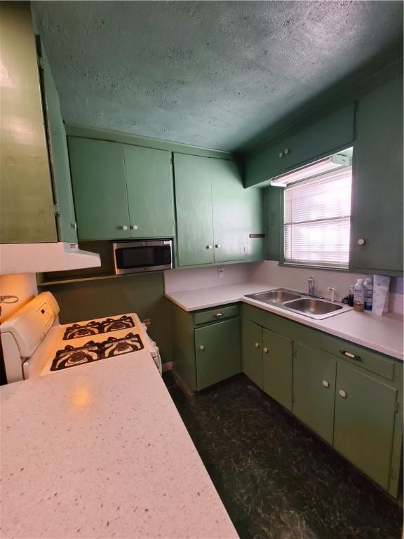 1041 Whitaker Dr, Corpus Christi, TX 78412 - kitchen with green cabinetry, a textured ceiling, stainless steel microwave, light countertops, and white gas range