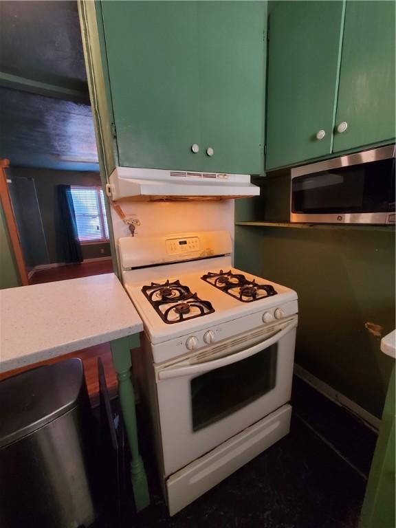 1041 Whitaker Dr, Corpus Christi, TX 78412 - kitchen with white range with gas cooktop, stainless steel microwave, green cabinetry, under cabinet range hood, and light countertops