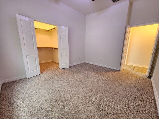 unfurnished bedroom featuring a walk in closet, carpet floors, and a closet