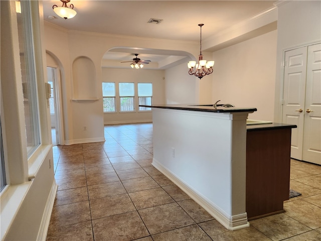 kitchen with decorative light fixtures, ornamental molding, light tile patterned floors, ceiling fan, and a center island with sink