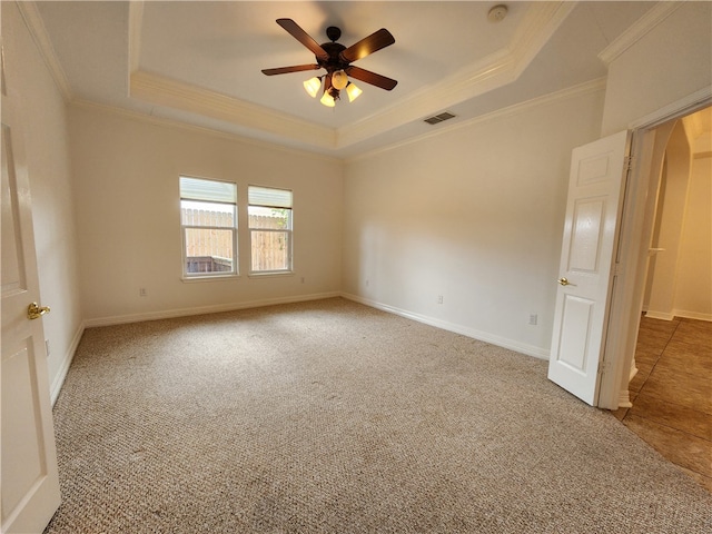 empty room featuring crown molding, a tray ceiling, carpet floors, and ceiling fan