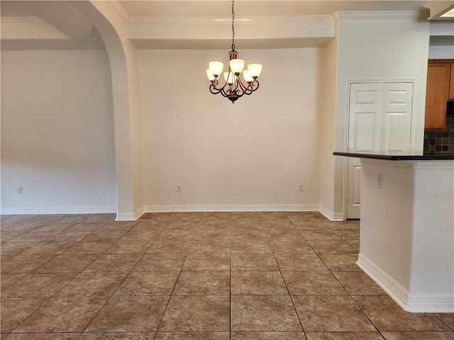 unfurnished dining area featuring an inviting chandelier, crown molding, and tile patterned flooring