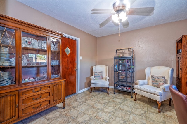 living area with a textured ceiling and ceiling fan