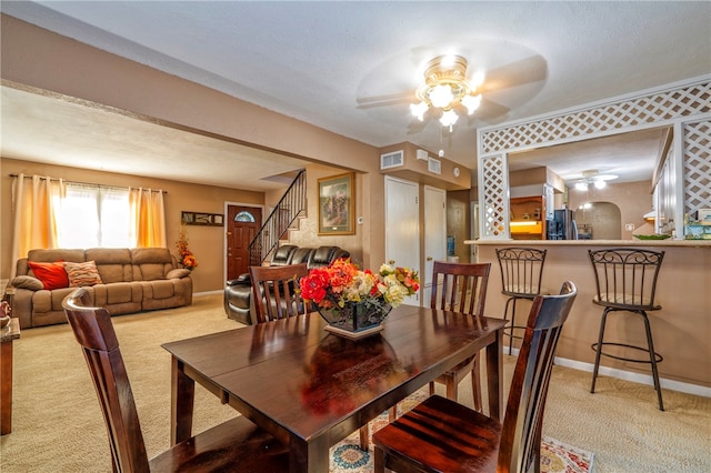 dining area with light carpet, a textured ceiling, and ceiling fan