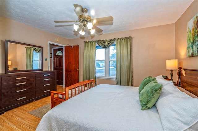 bedroom with a textured ceiling, light hardwood / wood-style flooring, and ceiling fan